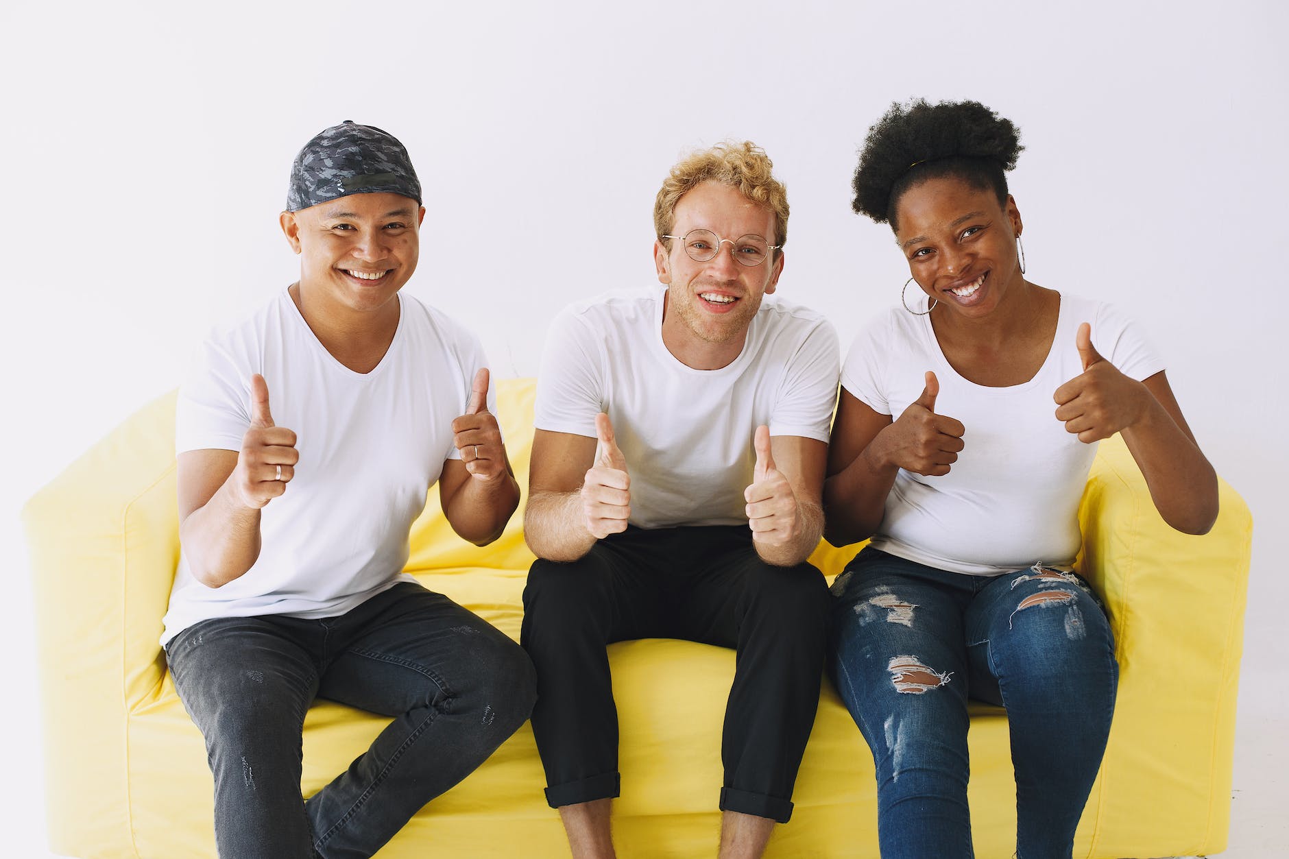smiling people sitting on couch showing thumbs up
