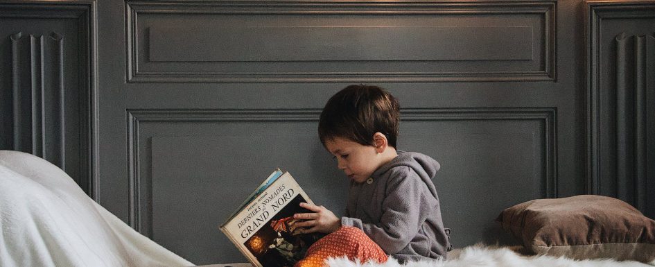boy in gray jacket reading book