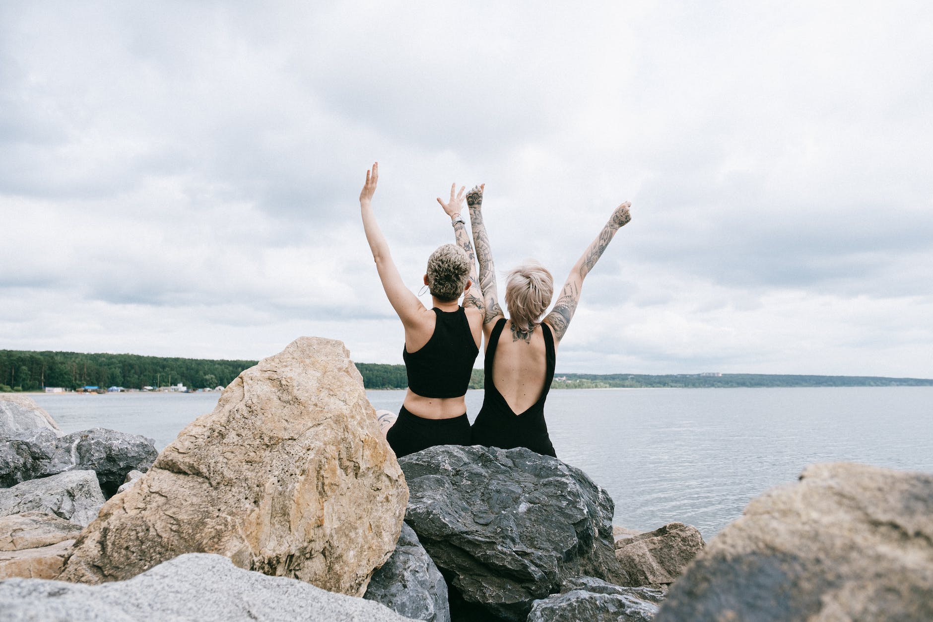 women sitting on rock while raising their hands