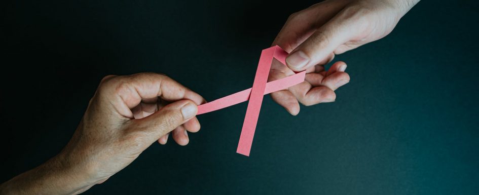 hands holding breast cancer pink paper ribbon